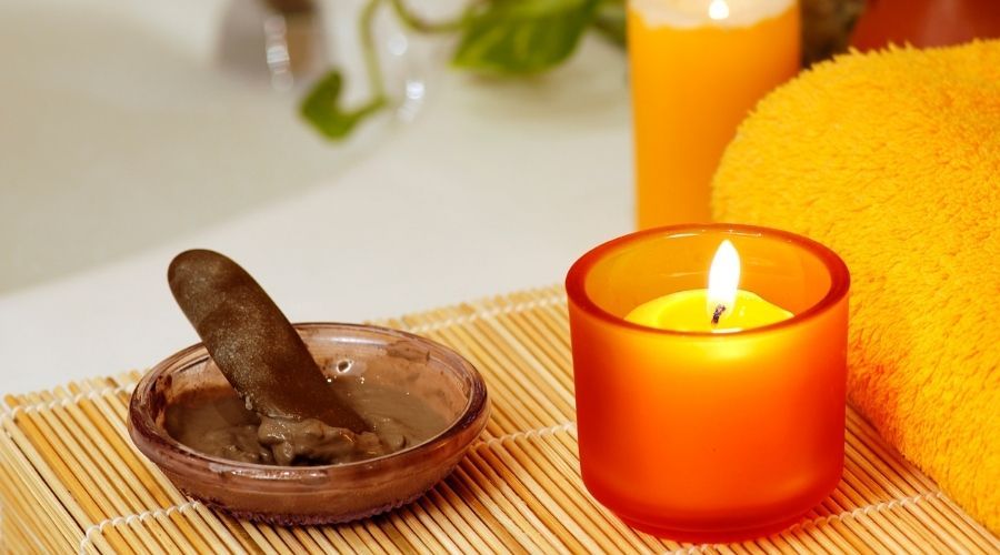 mud mask and candle on the side of a tub
