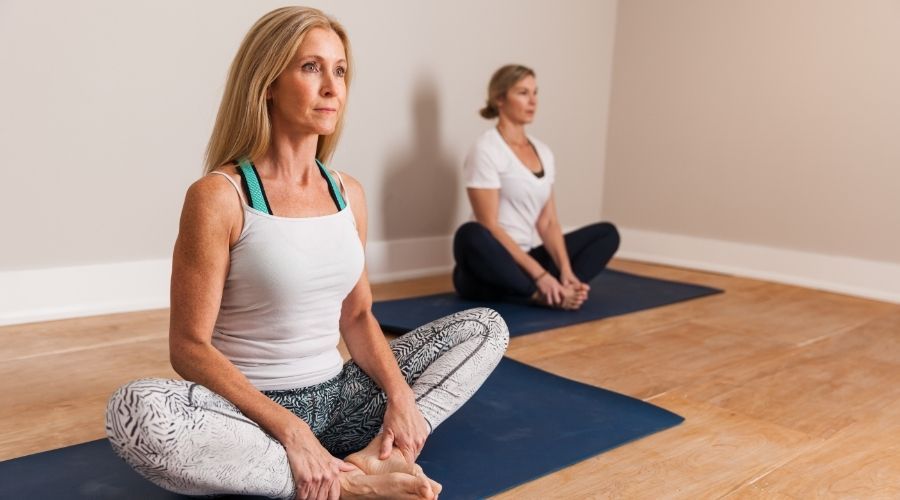 two women doing yoga on a hardwood floor