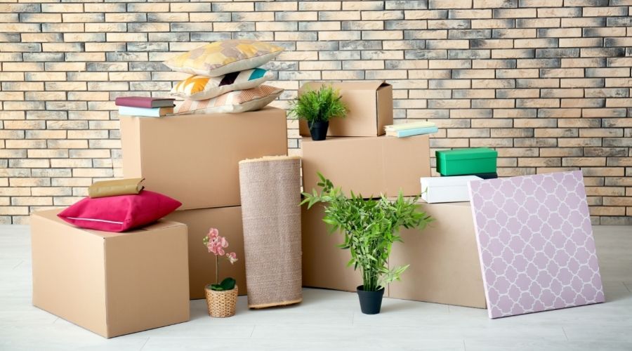 cardboard boxes full of house items in front of brick wall