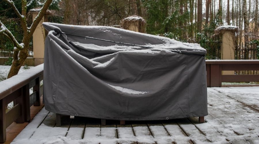 patio furniture with a cover in the snow