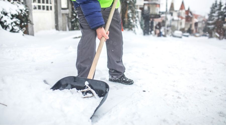 a man shovelling snow with a black and wooden shovel