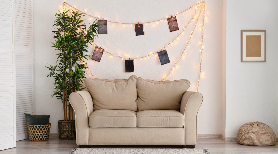 Interior of Room with Sofa and Glowing Garland with Photos on White Wall