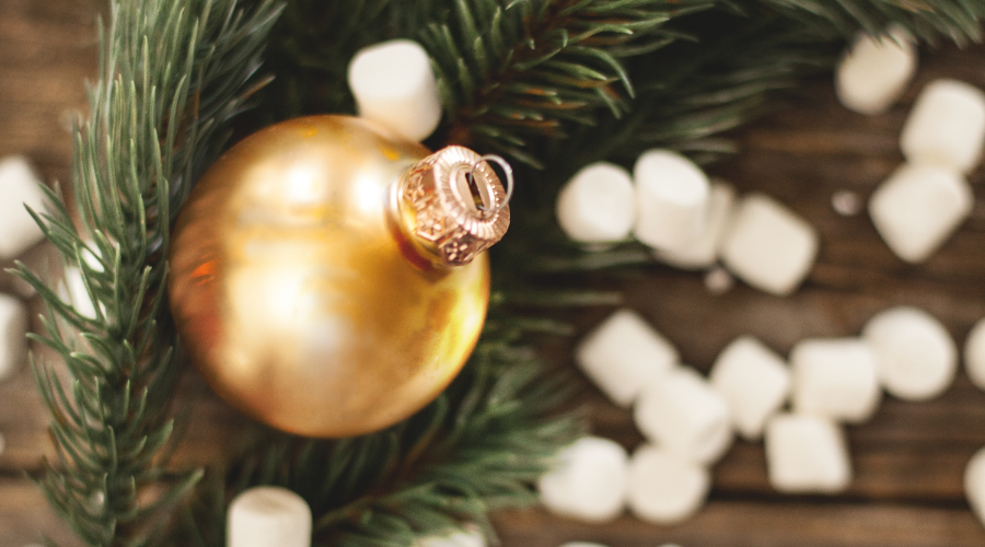 Gold christmas ball on a green branch with white marshmallow