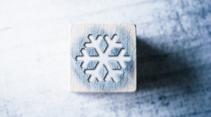 Snowflake Sign On A Blue Wooden Block On A Table