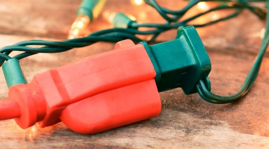 Christmas light string plugged into a red extension cord
