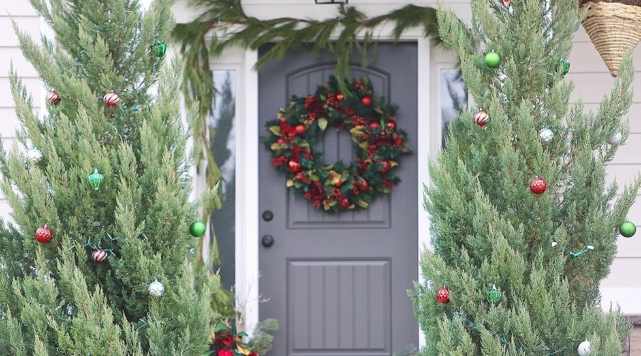front door decorated with wreath and Christmas trees
