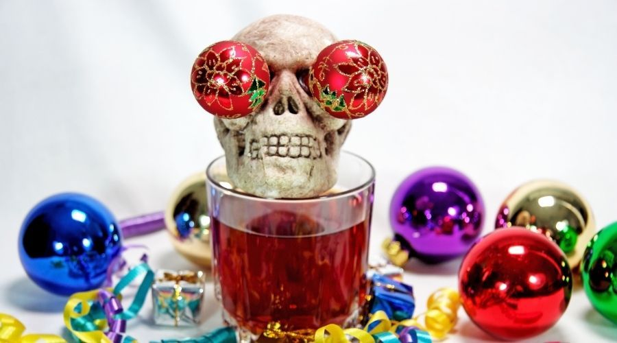 skeleton sitting on a cocktail glass surrounded with Christmas ornaments