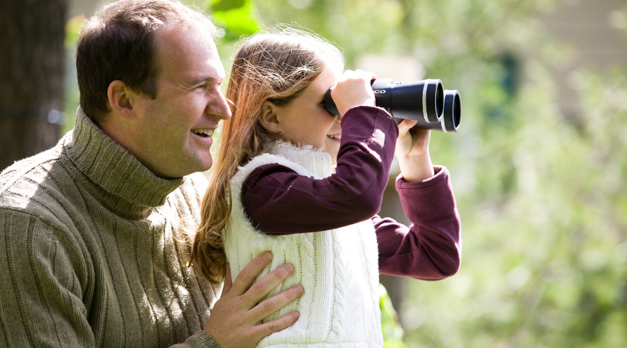 Father and daughter birdwatching outdoors