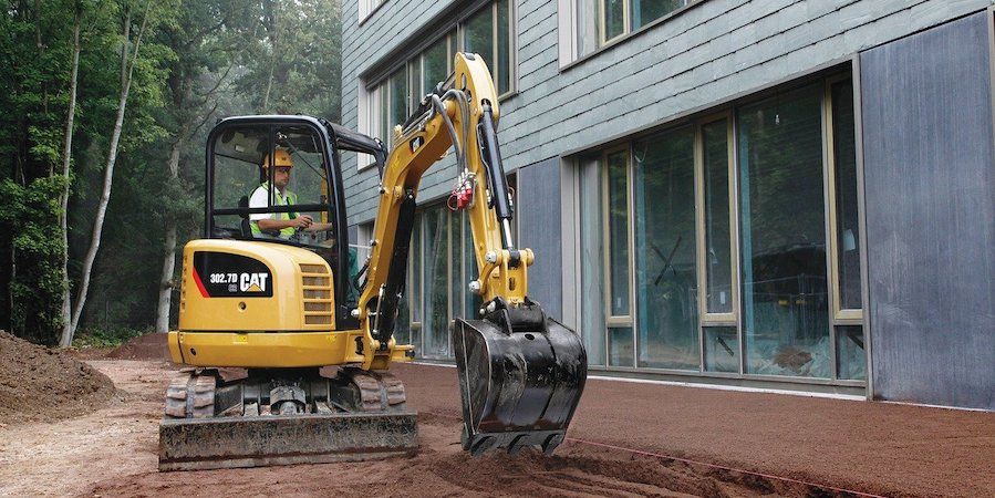 Mini excavator in front of house 
