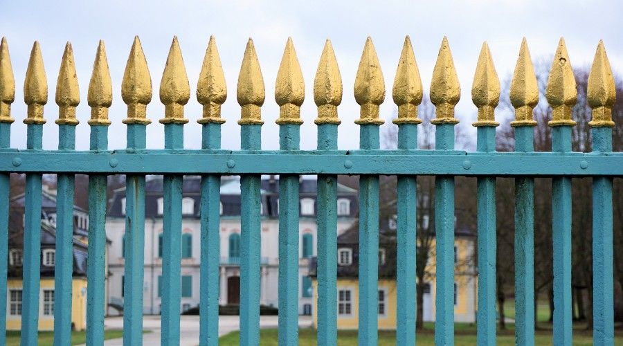 iron fence painted teal with gold accents