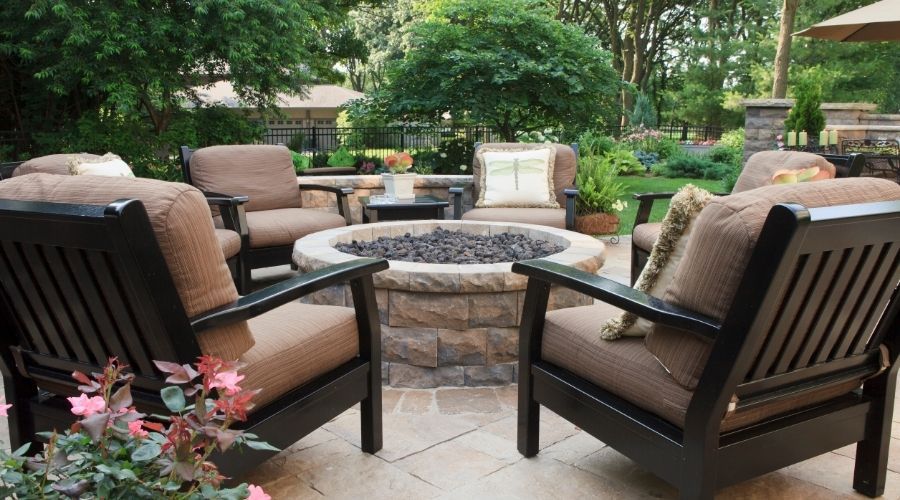 outdoor seating with thick chair cushions surrounding a stone fire pit on a stone patio