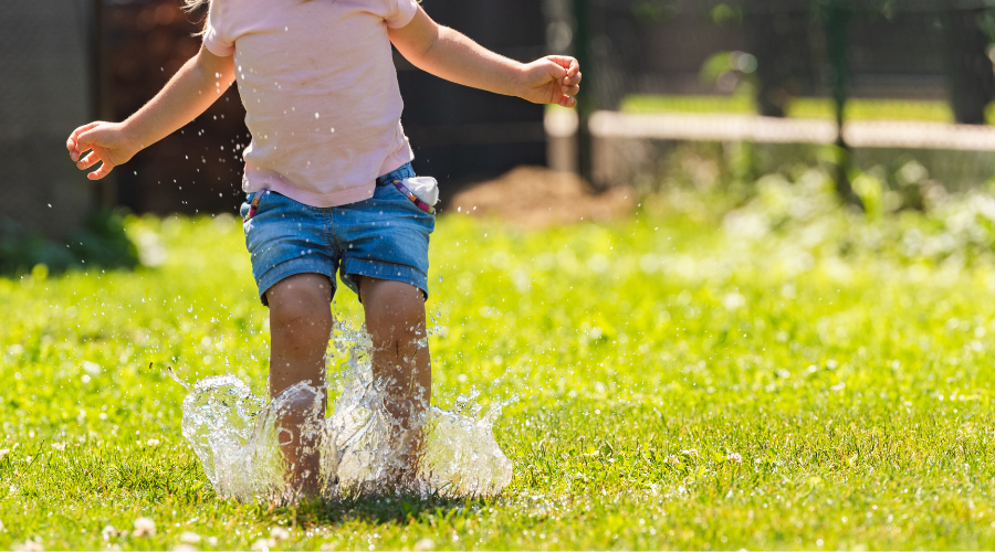 little girl splashing in overwatered lawn