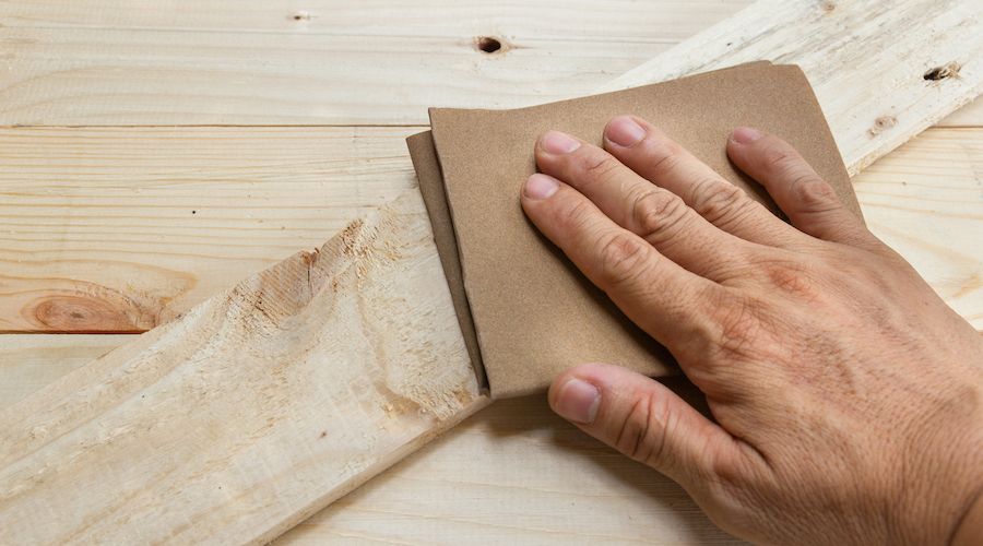 Worker Man Polishing Sandpaper Wood by hand.