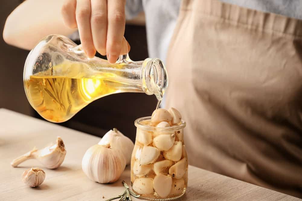 person pouring olive oil over garlic