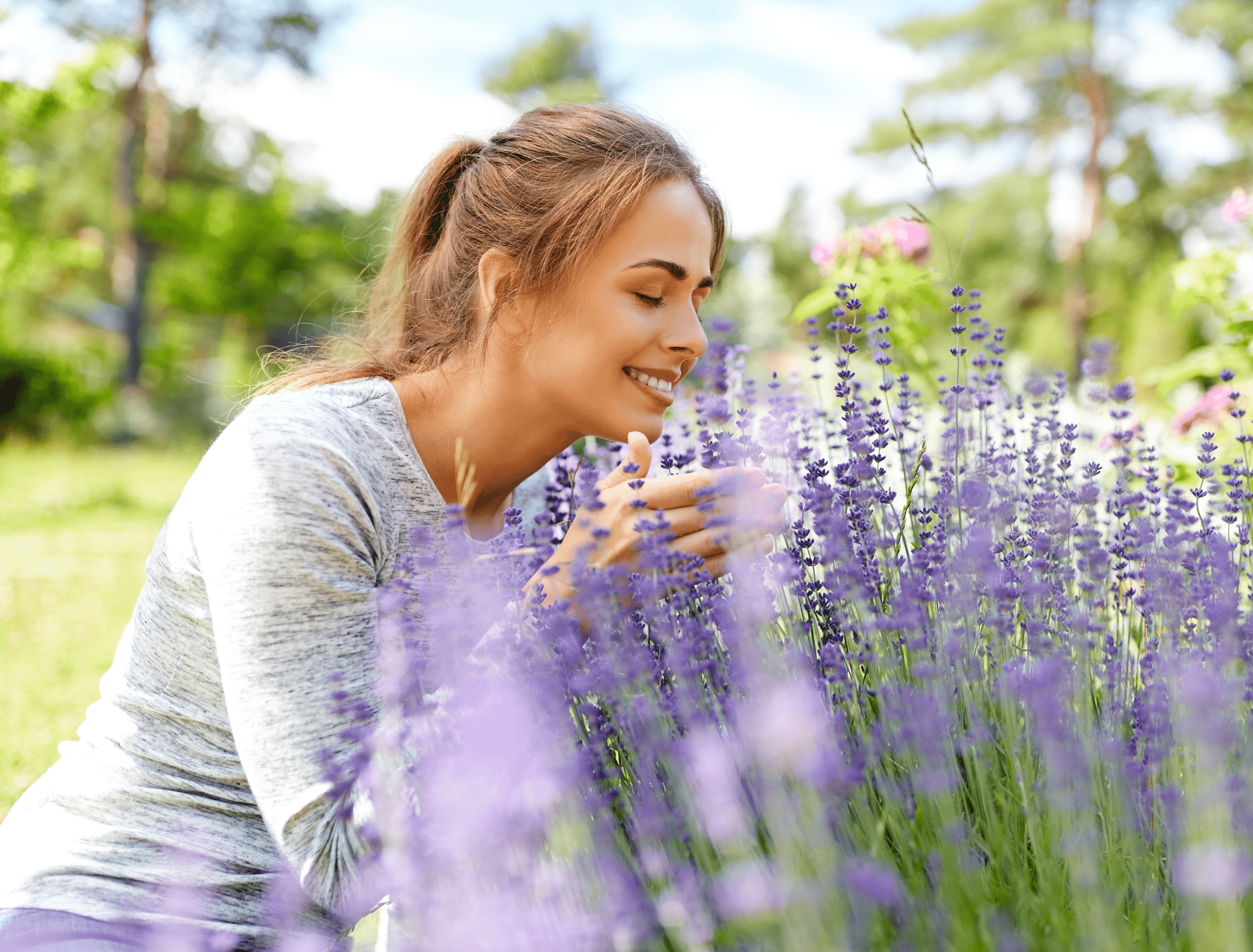 Young Woman Smelling Lavender Flowers in Garden