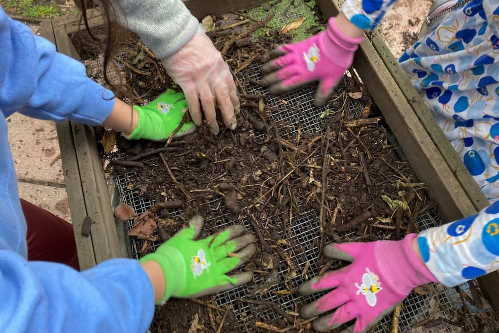 Gardeners sift compost in a community garden in New York