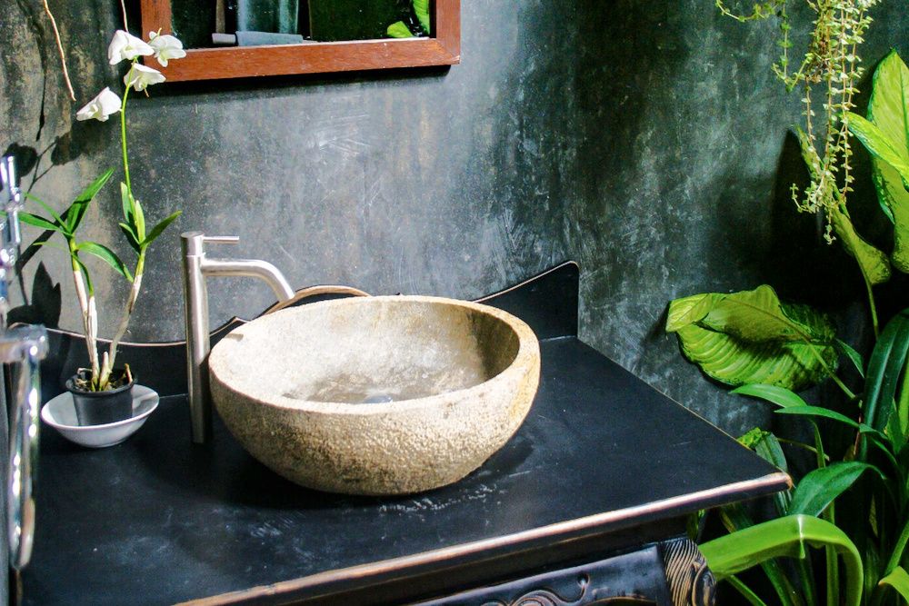 Luxury outdoor bathroom in tropical jungle with dark theme, green plants and exquisite furniture