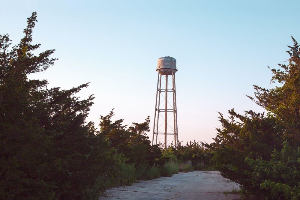 Water tower looms over a path that cuts through a wooded area