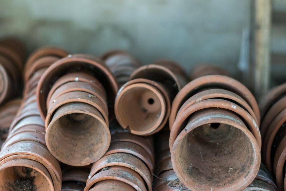 Many dirty terracotta pots lined up inside each other sideways