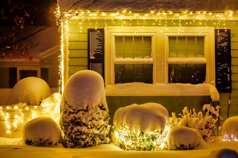 Beautiful house and garden under the snow. Christmas lights