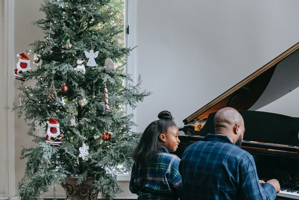A Father and Her Child Playing a Piano Near a Christmas Tree