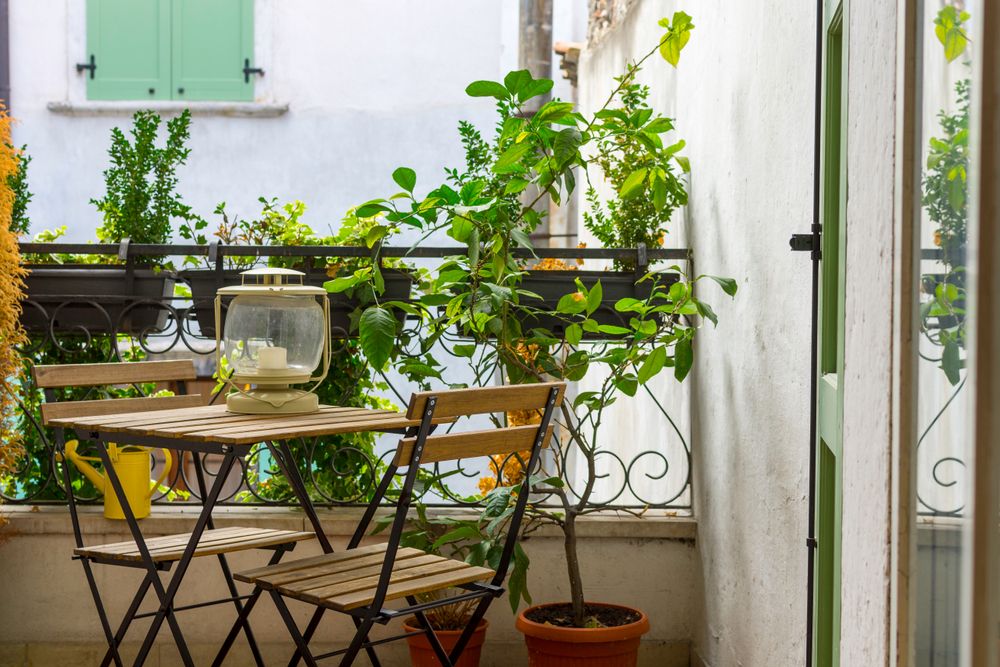 balcony with green potted plants and garden furniture.