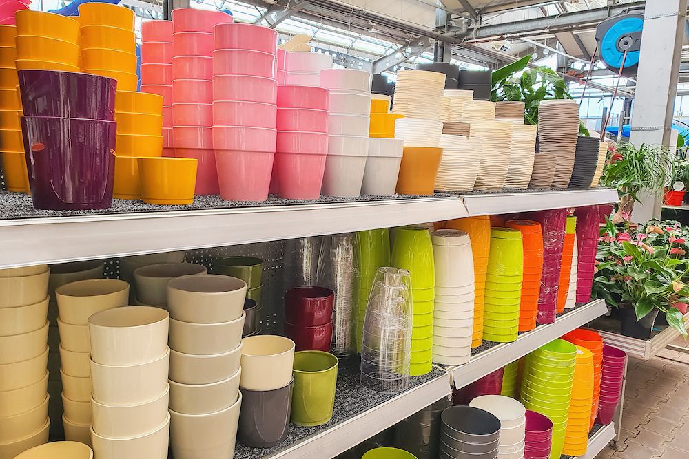 Variety of colorful ceramic and plastic flower pots on the shelf in a plant store. Shopping for trendy pot flowers and home interior design concept.
