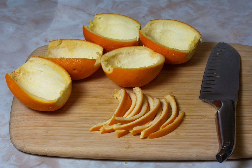 Orange peels on a chopping board with a knife