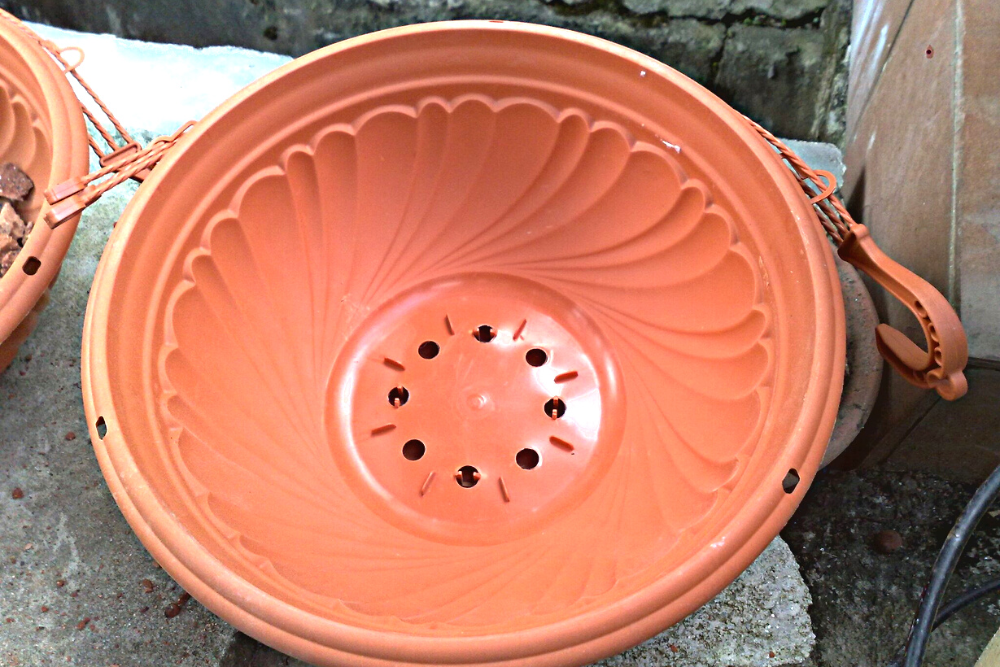 Terracotta-colored plastic hanging planter with drainage holes.