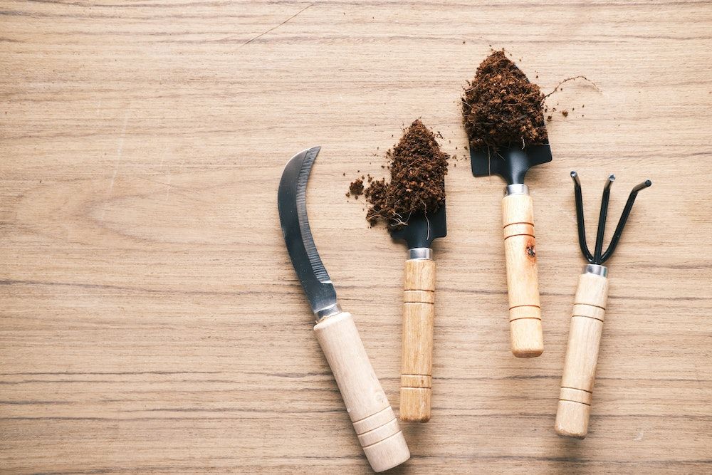 Garden Tools with Soil on Wooden Table