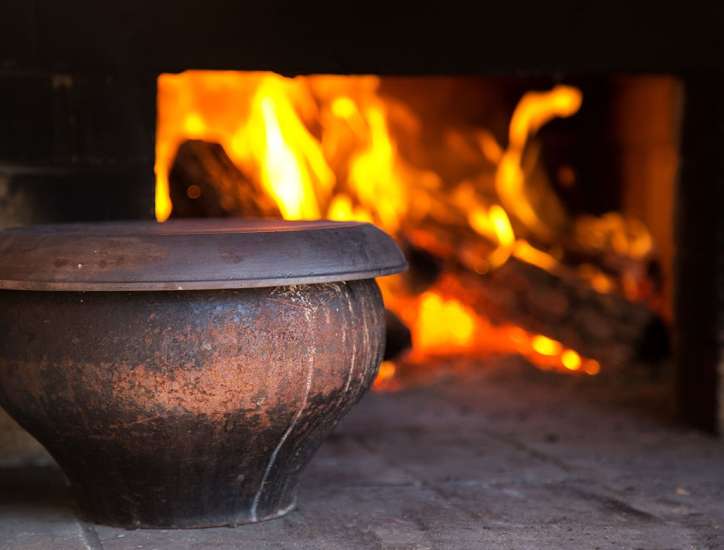 The fire in the old traditional russian village oven in a rustic style. Pot of soup near the burning wood