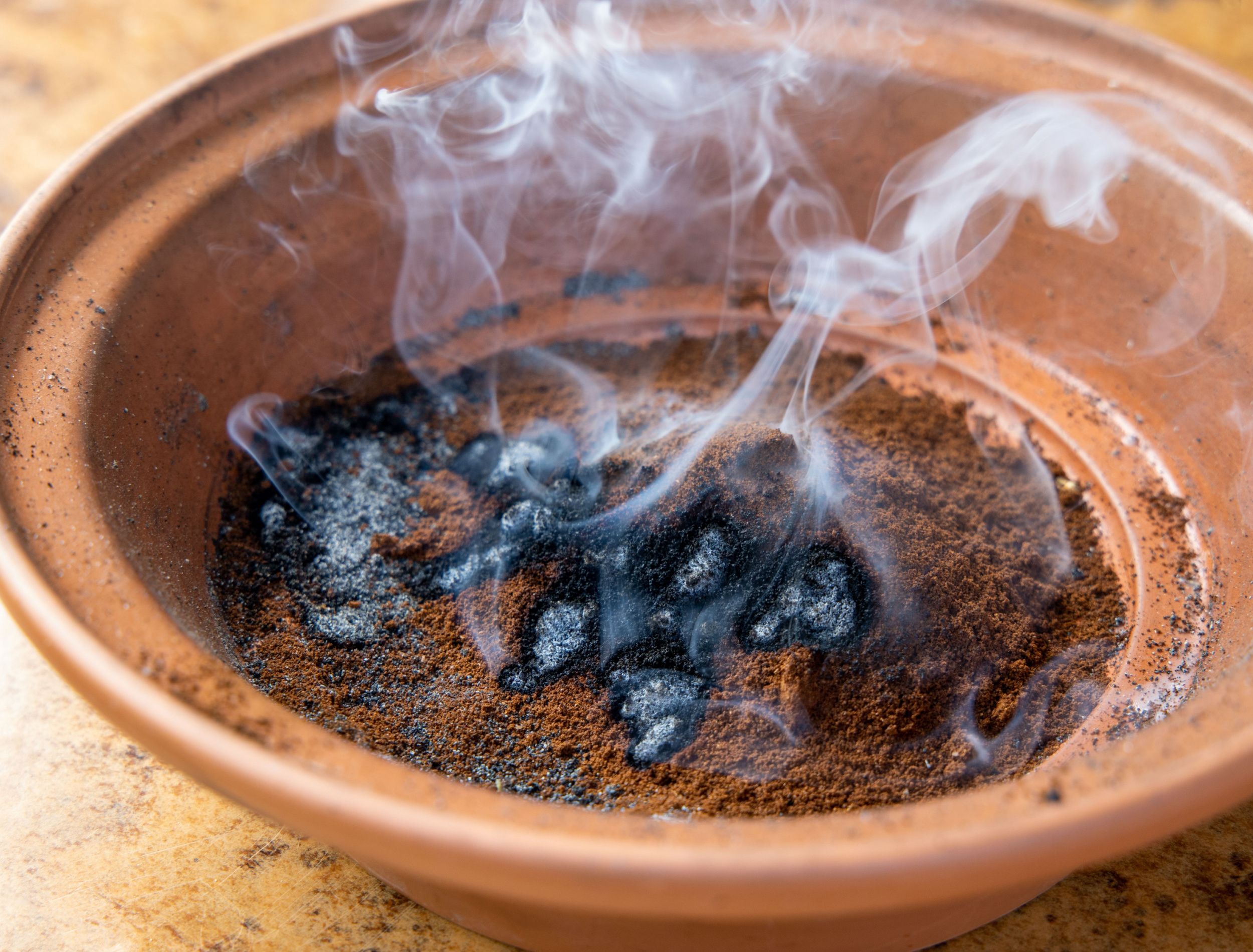 Coffee ground on fire and smoking from a ceramic dish