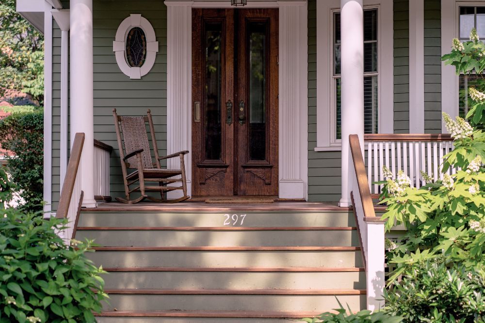 Front porch with green siding and a vintage wood front door