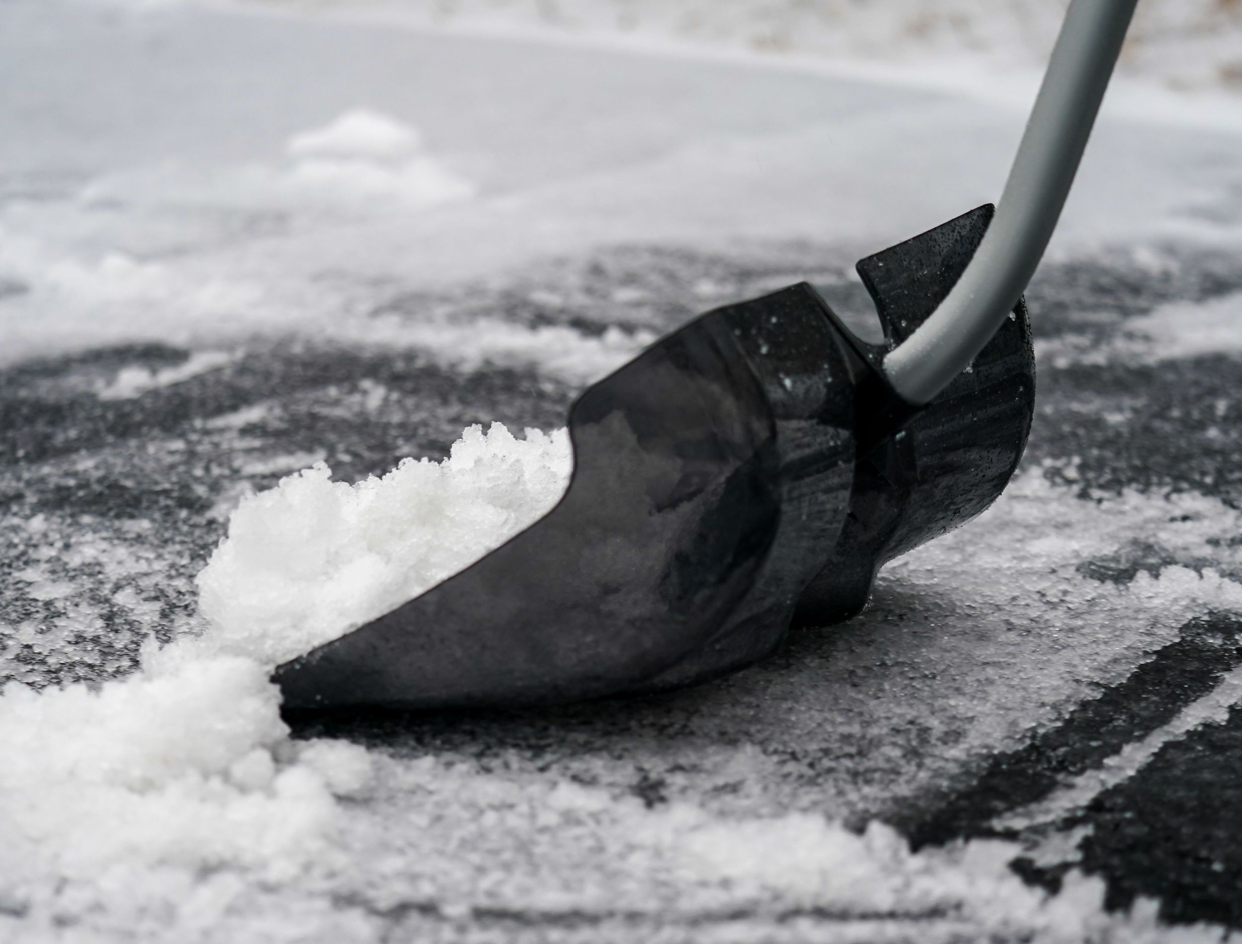 Ergonomic polycarbonate shovel clearing ice and sleet off a driveway