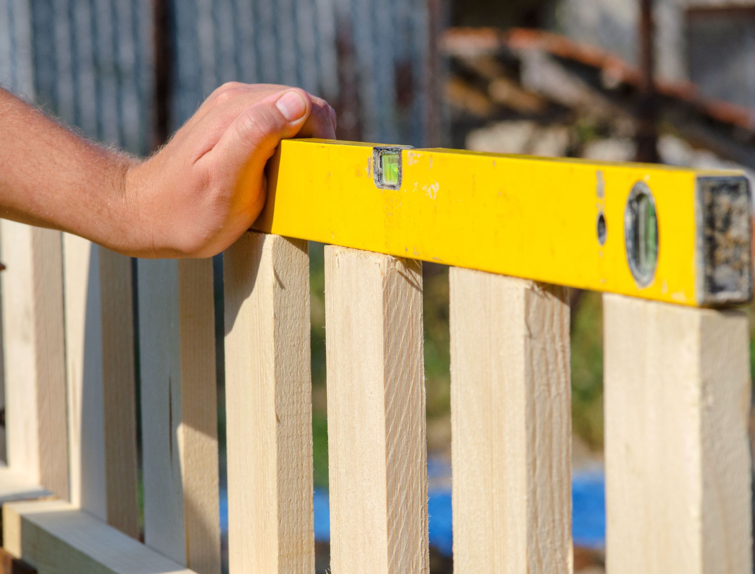 Man building a wooden fence and checking with spirit level
