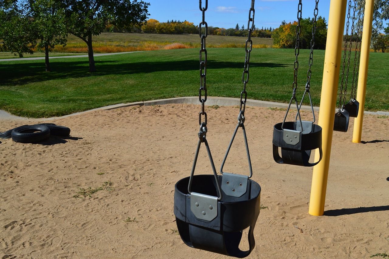Swing set with sand underneath it. 