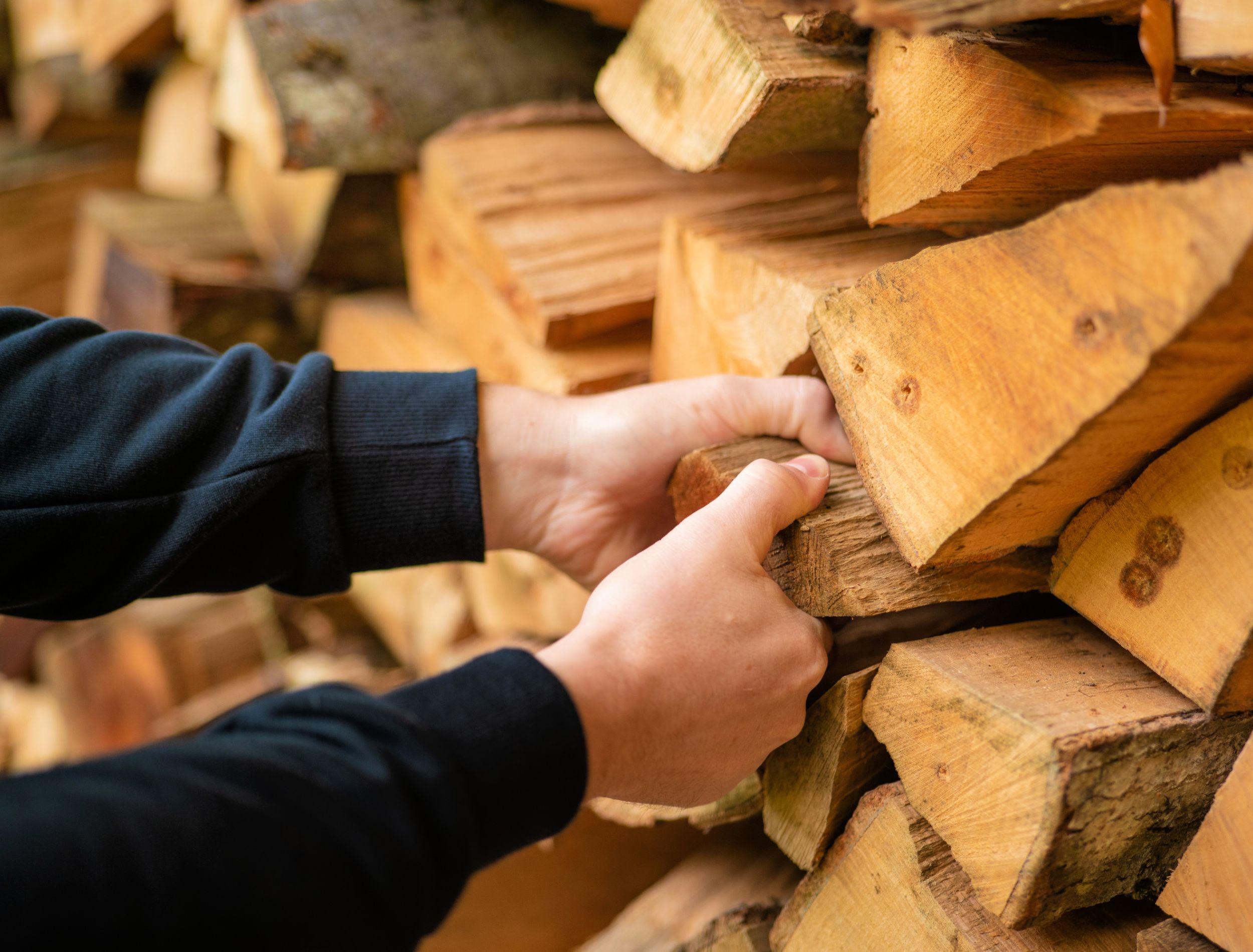 Heating season. Firewood.hands pulling a log from a woodshed. Male hands pulling a log from a woodshed.Heating season in Europe.Firewood and mens hands close-up.