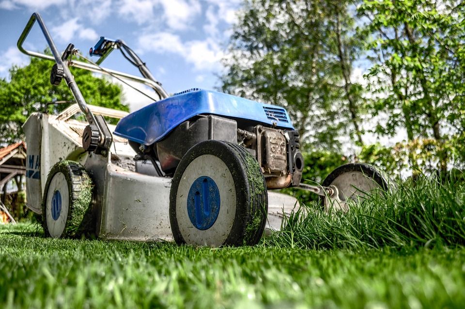 A lawn mower parked on a lawn, signifying preparations for aeration, a key lawn maintenance task.