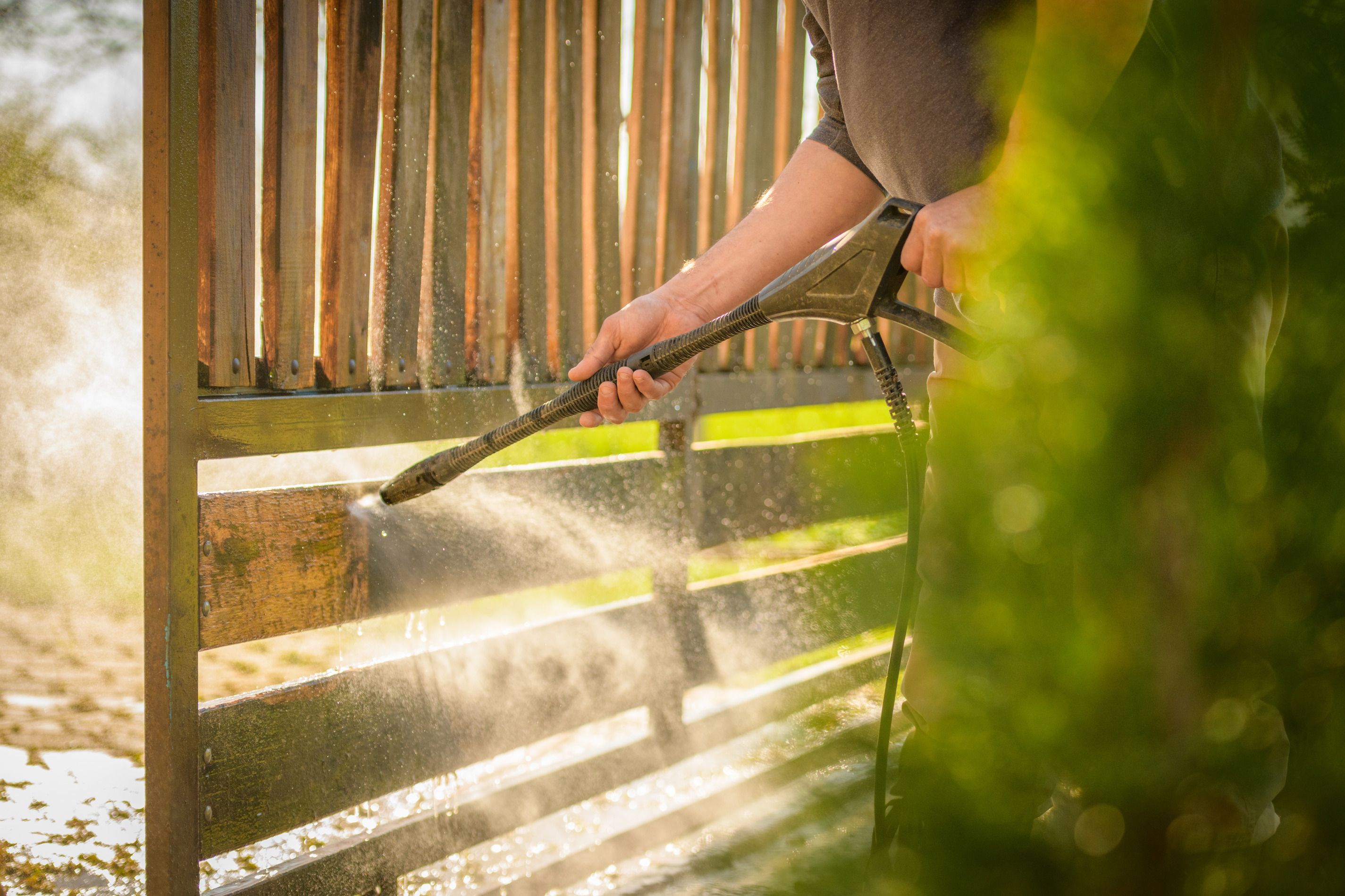 Man cleaning a fence using a pressur washer