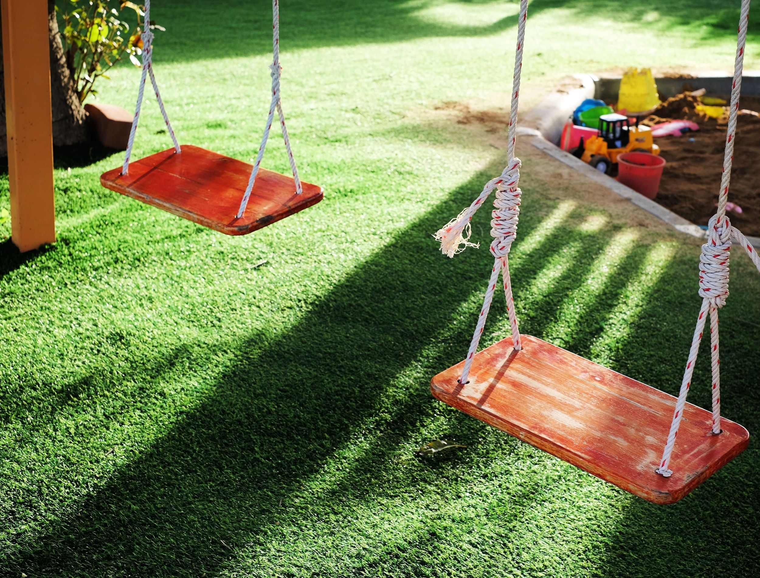 Two empty wooden swing with sunlight in playground.