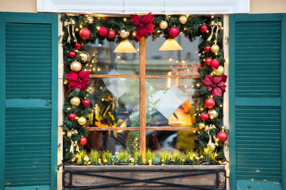A window shaped by evergreen and Christmas oranments