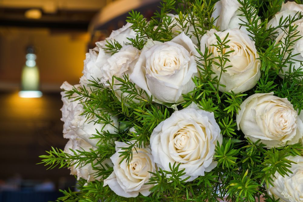 Floral arrangement with beautiful white roses and sprigs of asparagus fern