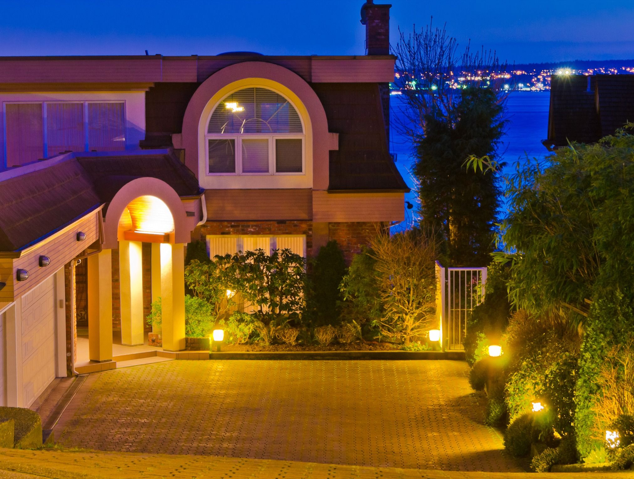 Luxury house with gorgeous night ocean view in Vancouver, Canada with illuminated driveway