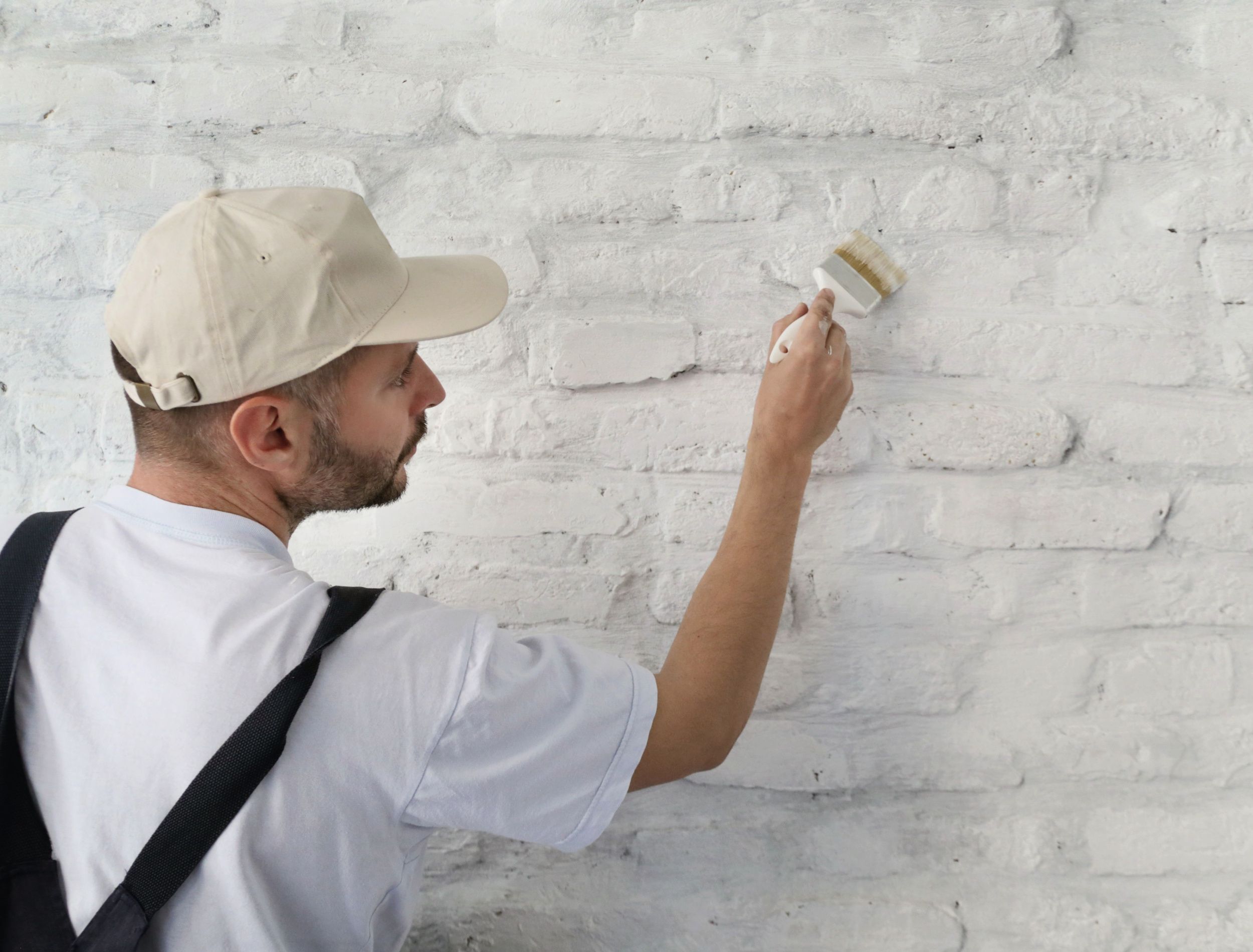 Painting a white brick wall with a paint brush
