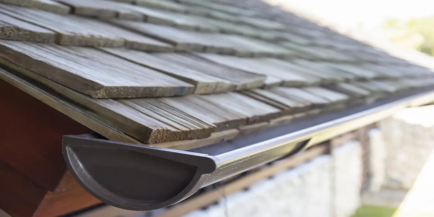 A gutter system under shingle roofing