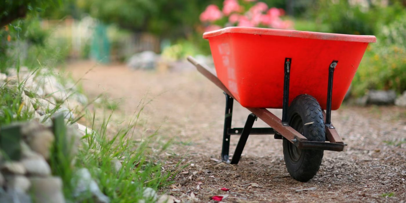Red plastic wheelbarrow on garden path