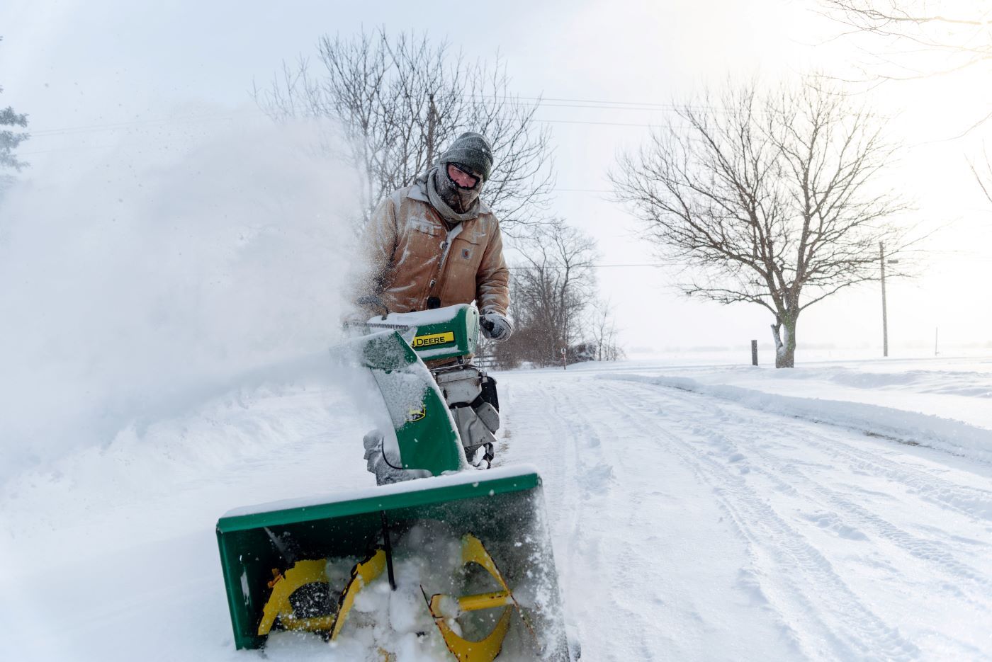 A person using a snow blower to clear snow on a road