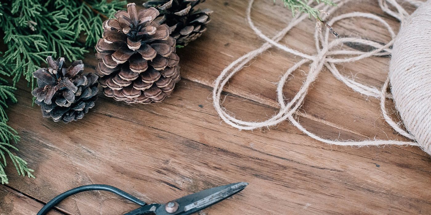 Making a wreath with greenery and pine coles twice and snips on table