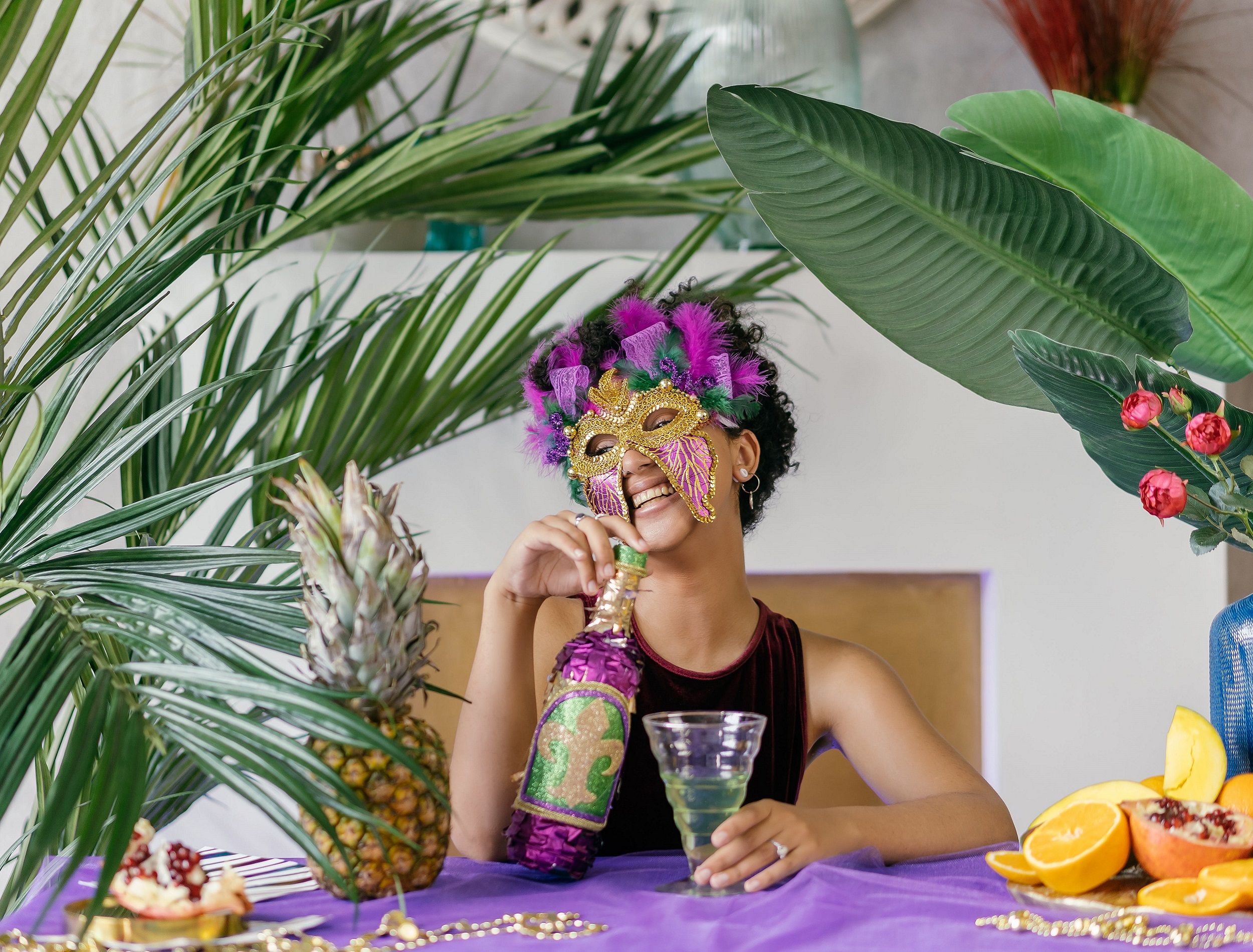 Mardi Gras party plant decor woman sitting at table with purple tablecloth