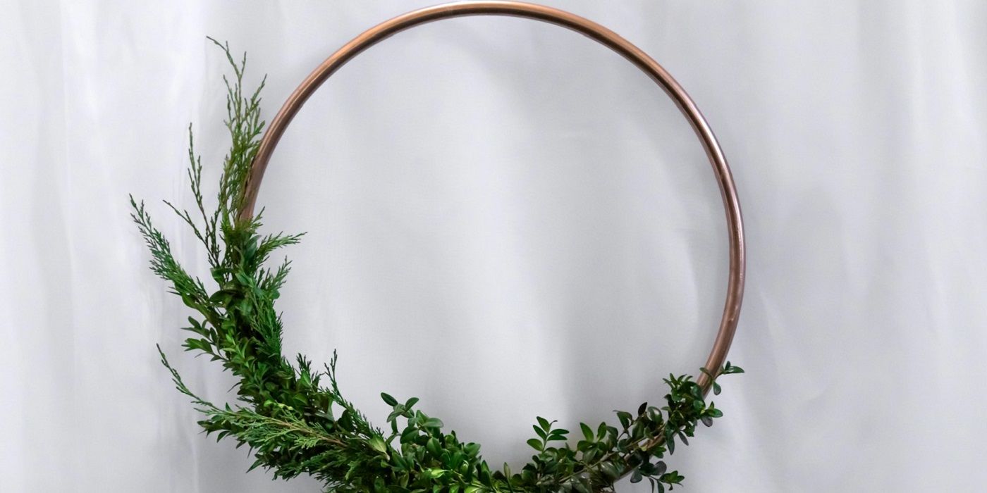 Minimalist wreath with gold hoop and greenery on a white background